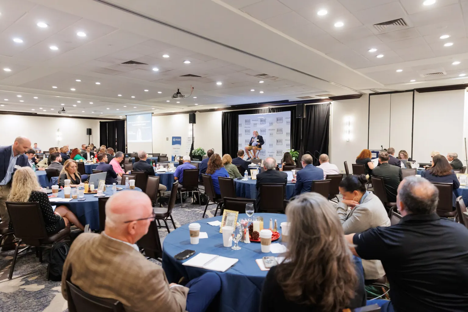 A ballroom full of guests at round tables during a corporate event