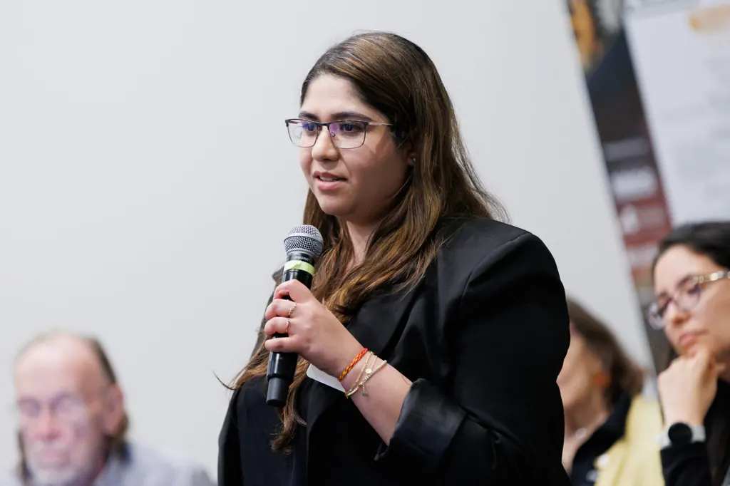 A woman asking a question with a microphone during a conference session