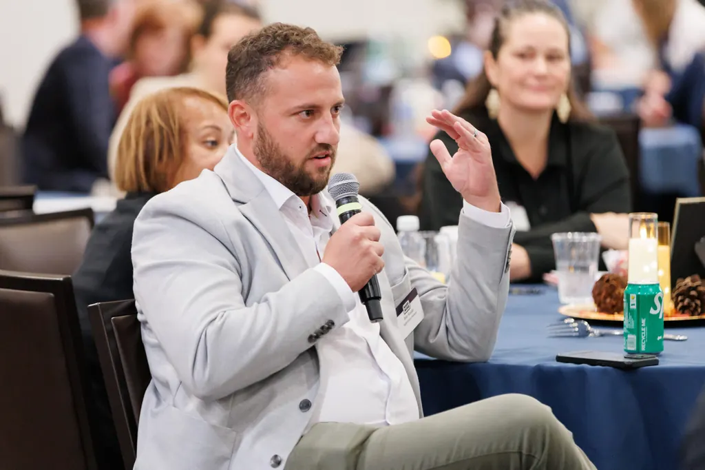 Attendees seated at a table during an event, a microphone passed between them